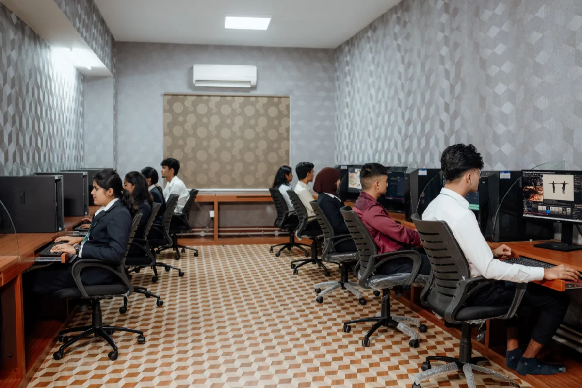 Students in formal attire training at computer workstations inside a post-production editing lab at SAFA